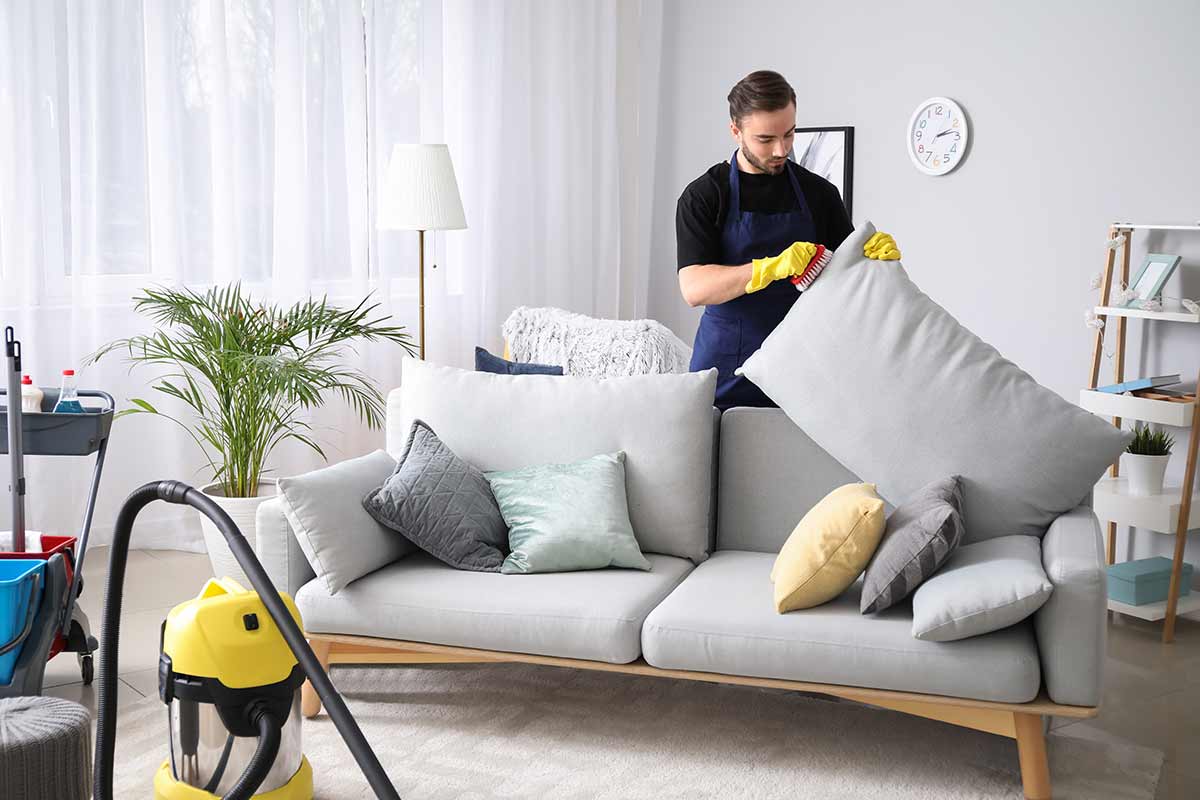 Female janitor with vacuum cleaner in room