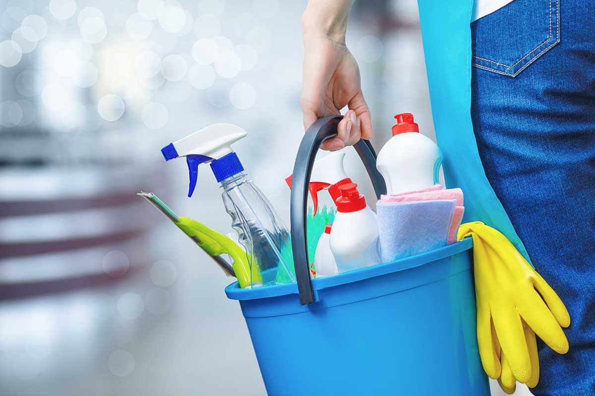 shutterstock_1909047961 holding cleaning products and tools on bucket, close up